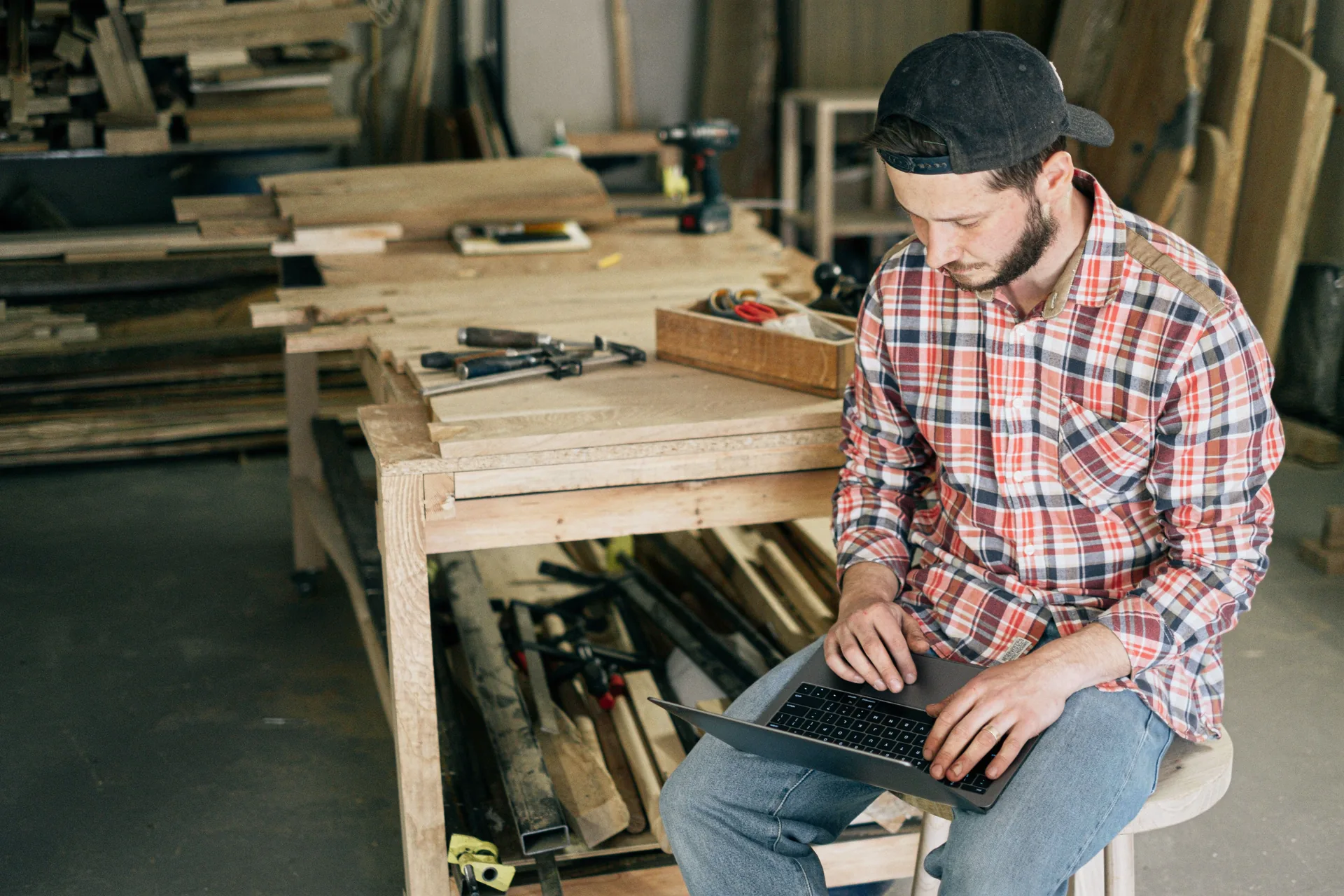 Carpenter checking his website on a laptop in the workshop