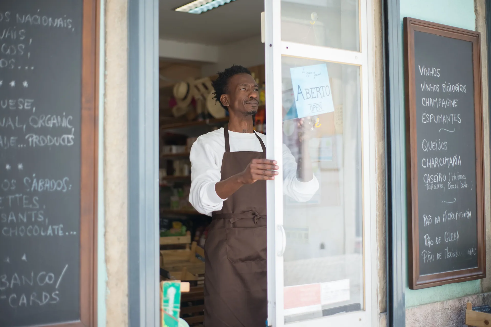 Grocer in an apron opening the shop door for the day