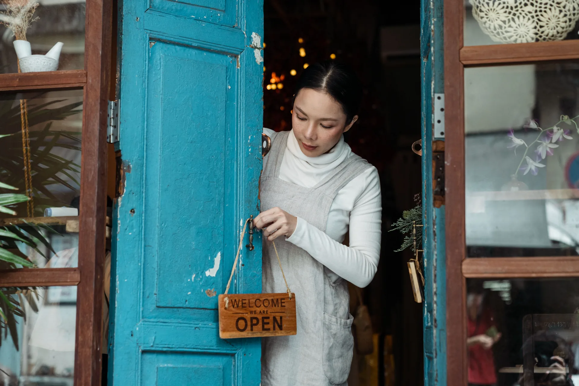 Shop owner setting the open sign on a blue door