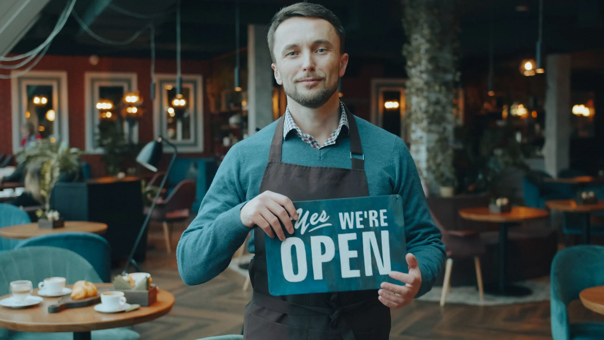 Cafe owner holding a We're Open sign